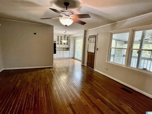 unfurnished living room with ceiling fan, crown molding, dark wood-type flooring, and a textured ceiling