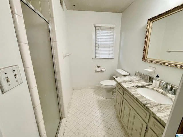 bathroom with tile patterned flooring, vanity, a shower with shower door, and toilet