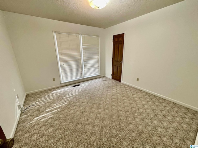 empty room with light carpet and a textured ceiling