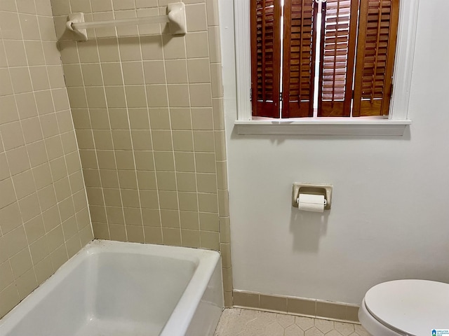 bathroom with tile patterned flooring, toilet, and a bath