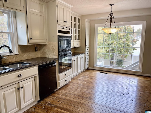 kitchen featuring black appliances, plenty of natural light, and white cabinets