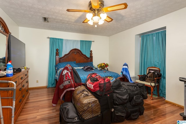 bedroom featuring ceiling fan, wood-type flooring, and a textured ceiling