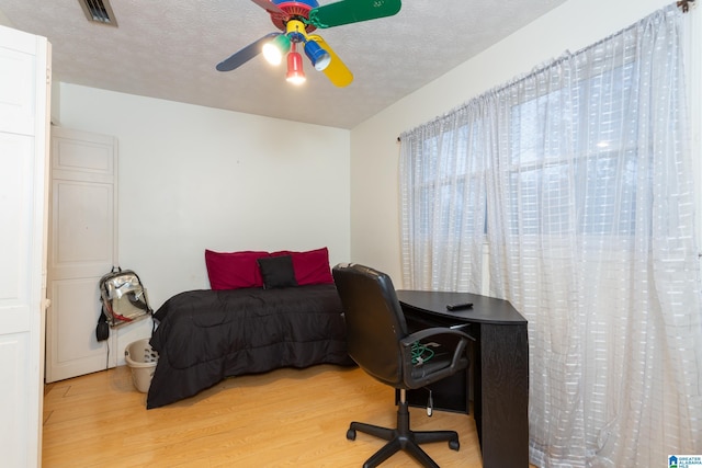 bedroom with ceiling fan, light hardwood / wood-style floors, and a textured ceiling