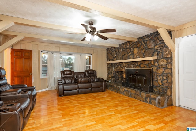 living room with hardwood / wood-style floors, a textured ceiling, and a stone fireplace