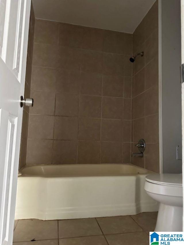 bathroom with tile patterned floors, toilet, and tiled shower / bath