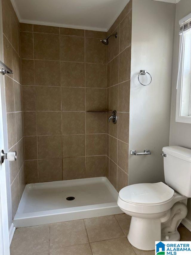 bathroom featuring a tile shower, tile patterned flooring, a healthy amount of sunlight, and toilet