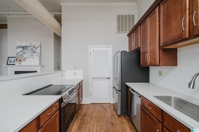 kitchen with backsplash, crown molding, sink, light hardwood / wood-style floors, and stainless steel appliances