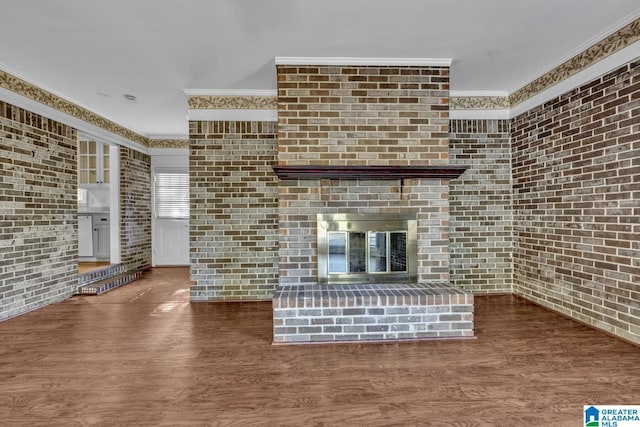 unfurnished living room featuring dark hardwood / wood-style flooring, crown molding, and brick wall