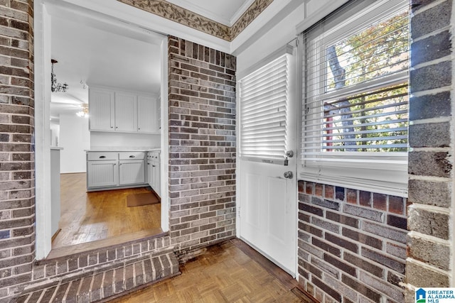 bathroom with ceiling fan, parquet floors, crown molding, and brick wall