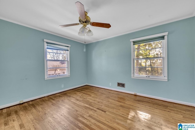 spare room featuring a wealth of natural light, ornamental molding, and light wood-type flooring