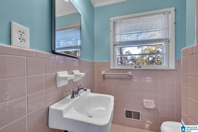 bathroom with toilet, sink, tile walls, and ornamental molding