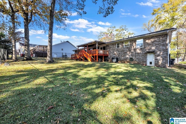 rear view of property with a lawn, central AC unit, and a wooden deck