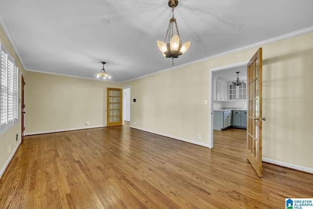 empty room with ceiling fan with notable chandelier, light hardwood / wood-style floors, ornamental molding, and french doors