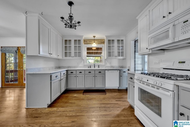 kitchen featuring white appliances, pendant lighting, hardwood / wood-style flooring, an inviting chandelier, and white cabinets