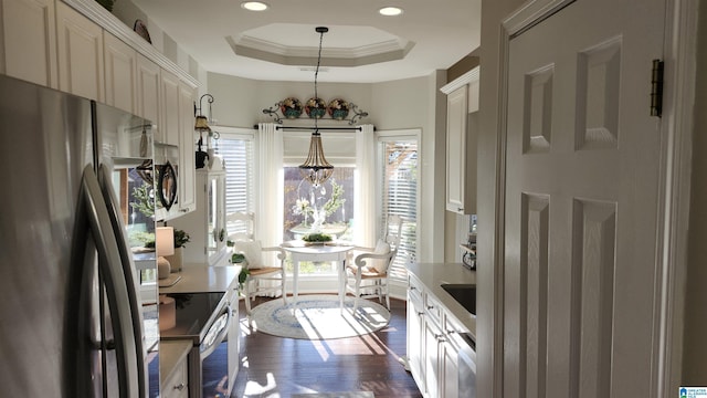 kitchen with crown molding, hanging light fixtures, a tray ceiling, a notable chandelier, and stainless steel appliances