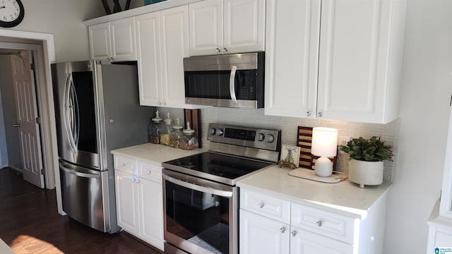 kitchen with white cabinets, dark hardwood / wood-style floors, appliances with stainless steel finishes, and tasteful backsplash