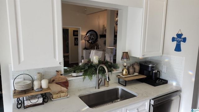 kitchen featuring backsplash, sink, stainless steel dishwasher, light stone counters, and white cabinetry