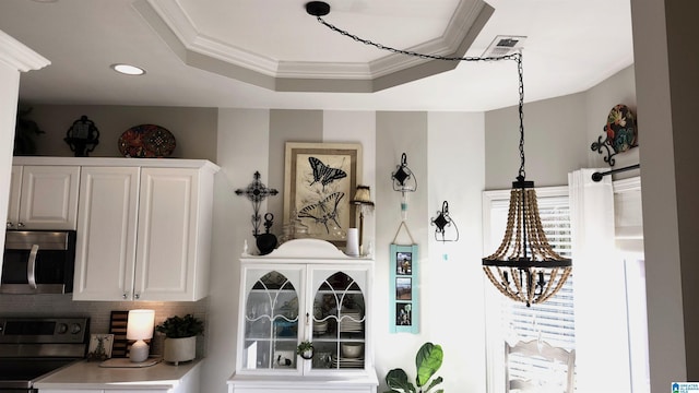 interior space with a tray ceiling, decorative backsplash, white cabinetry, and range