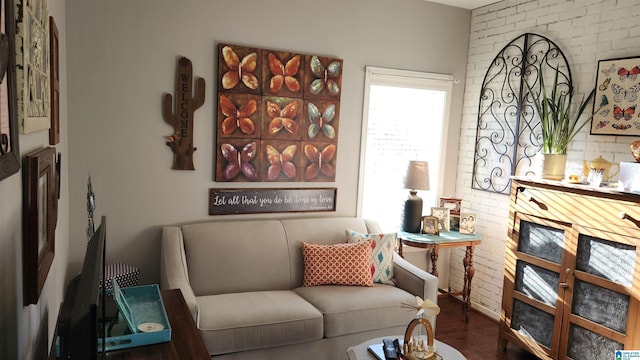 living area featuring hardwood / wood-style floors and brick wall