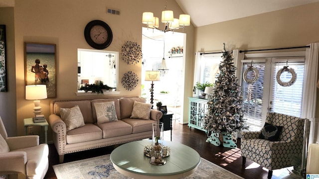 living room with a chandelier, dark wood-type flooring, vaulted ceiling, and a healthy amount of sunlight