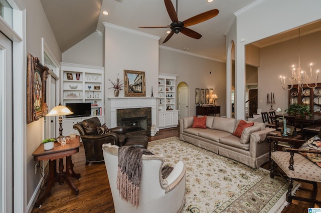 living room with ceiling fan with notable chandelier, crown molding, high vaulted ceiling, dark hardwood / wood-style floors, and a tiled fireplace