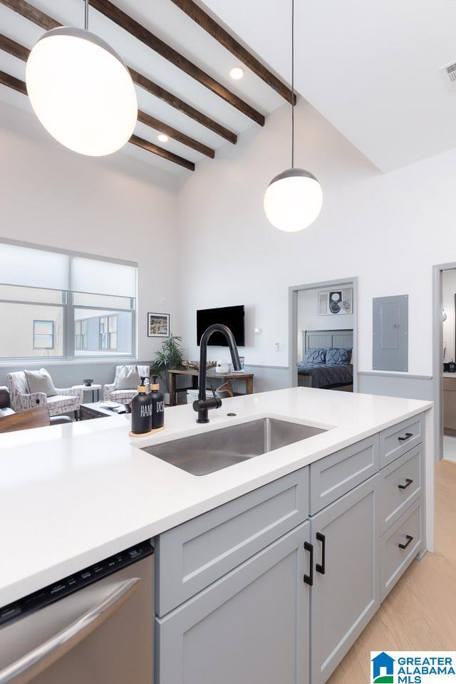 kitchen featuring stainless steel dishwasher, sink, beam ceiling, decorative light fixtures, and gray cabinets