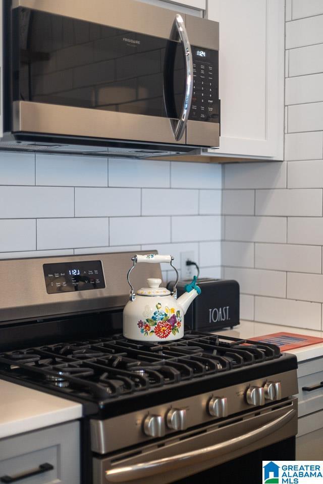 kitchen with decorative backsplash, white cabinets, and stainless steel appliances