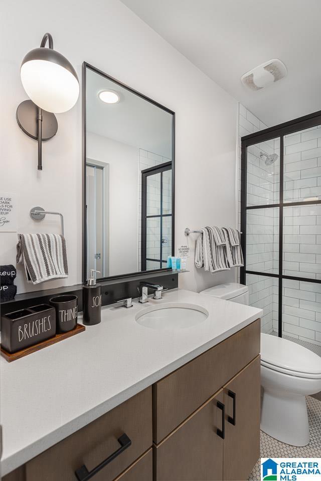 bathroom with tile patterned flooring, vanity, toilet, and walk in shower