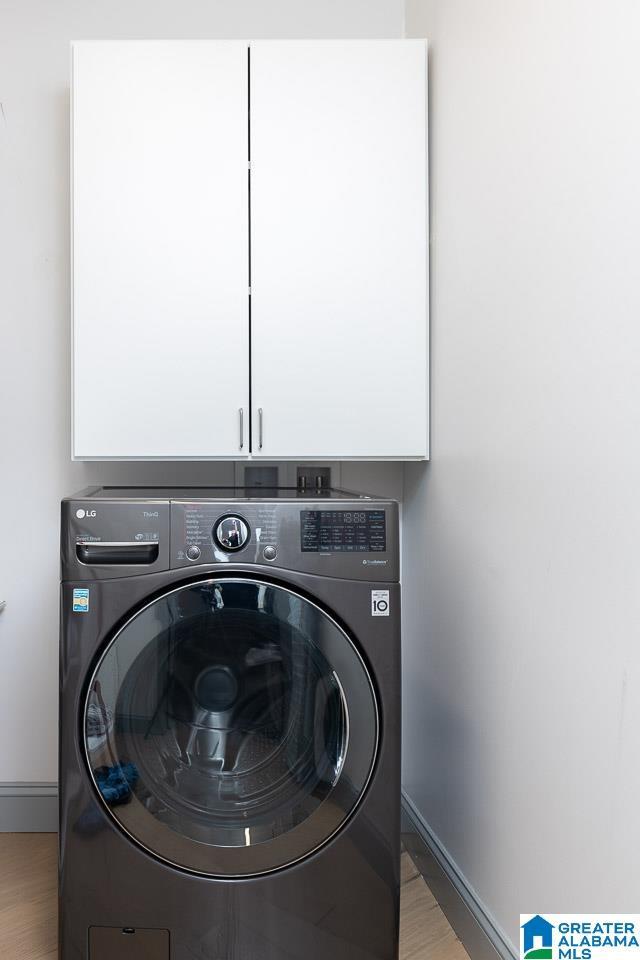 laundry area with cabinets, washer / clothes dryer, and light hardwood / wood-style flooring