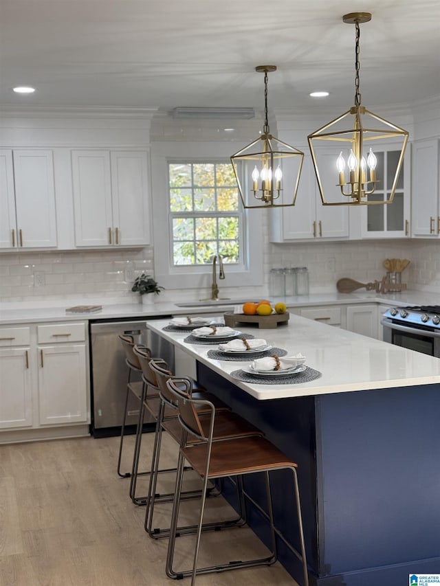 kitchen featuring dishwasher, white cabinets, hanging light fixtures, light hardwood / wood-style floors, and a breakfast bar area