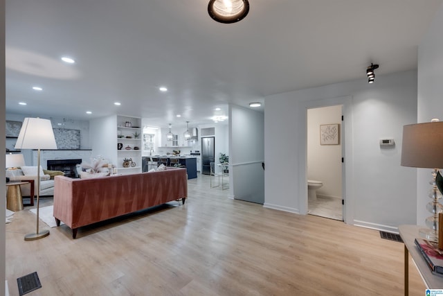 living room with a fireplace and light wood-type flooring