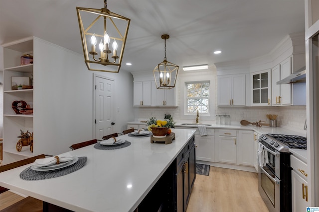 kitchen featuring white cabinetry, a center island, pendant lighting, and stainless steel gas range