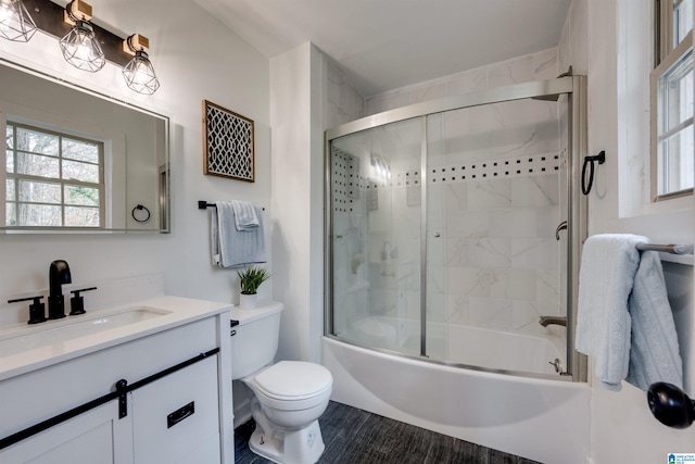 full bathroom with vanity, bath / shower combo with glass door, and toilet