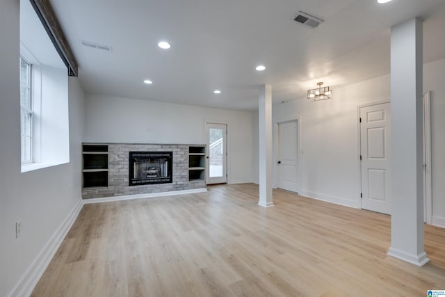 unfurnished living room with a brick fireplace and light hardwood / wood-style flooring