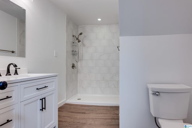 bathroom with toilet, hardwood / wood-style floors, vanity, and tiled shower