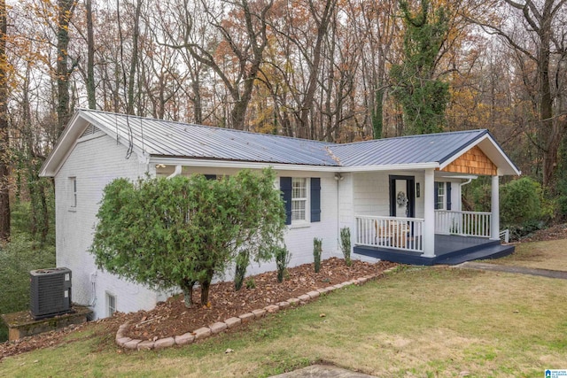 ranch-style home with cooling unit, covered porch, and a front lawn