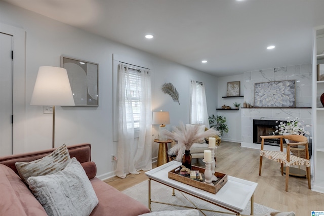 living room with a tile fireplace and light hardwood / wood-style floors