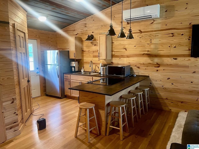 kitchen with sink, light brown cabinets, a wall mounted AC, stainless steel fridge, and vaulted ceiling
