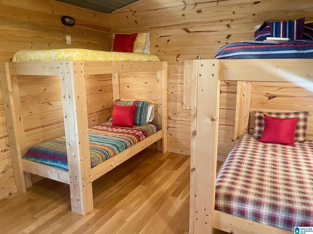 bedroom with hardwood / wood-style floors and wooden walls