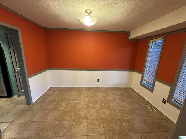 spare room with a textured ceiling and crown molding