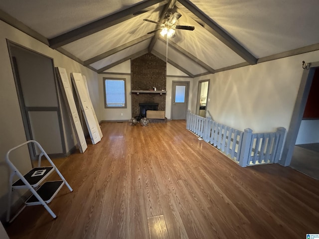 unfurnished living room featuring a fireplace, hardwood / wood-style floors, lofted ceiling with beams, and ceiling fan