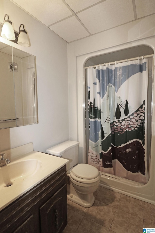 bathroom with a paneled ceiling, vanity, tile patterned floors, toilet, and curtained shower