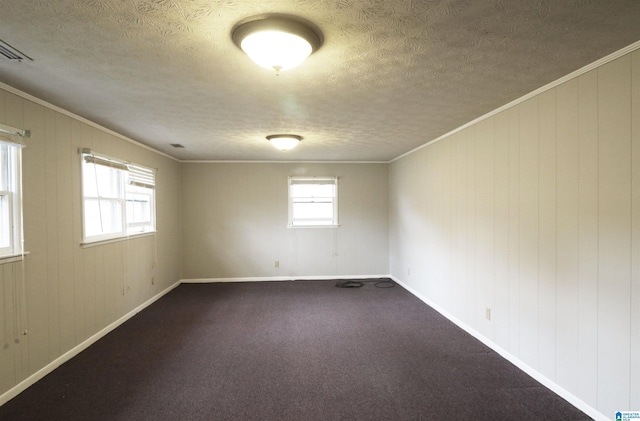 spare room with crown molding, wood walls, carpet floors, and a textured ceiling