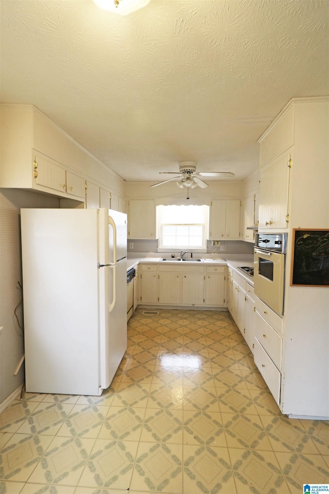 kitchen with a textured ceiling, stainless steel appliances, ceiling fan, and sink