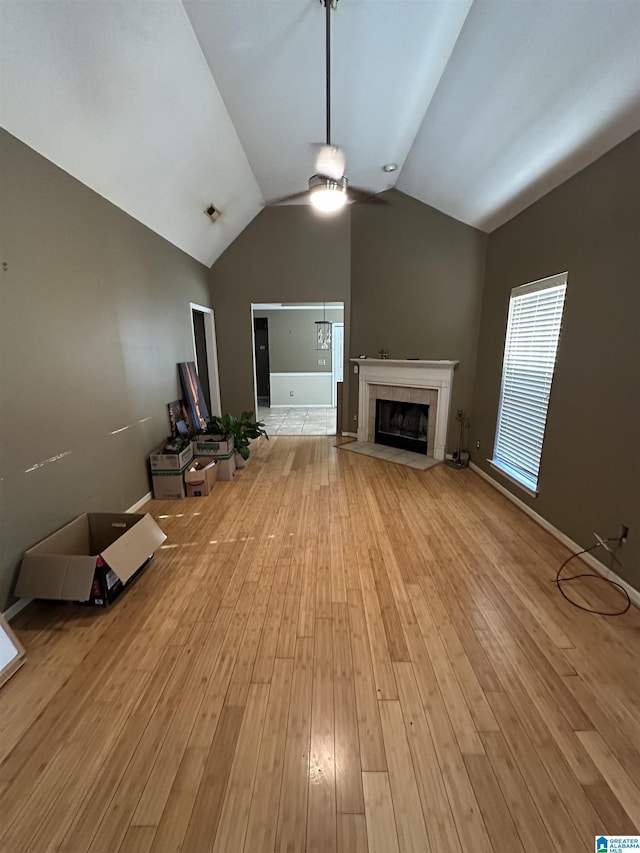 unfurnished living room featuring a tile fireplace, light hardwood / wood-style floors, and lofted ceiling