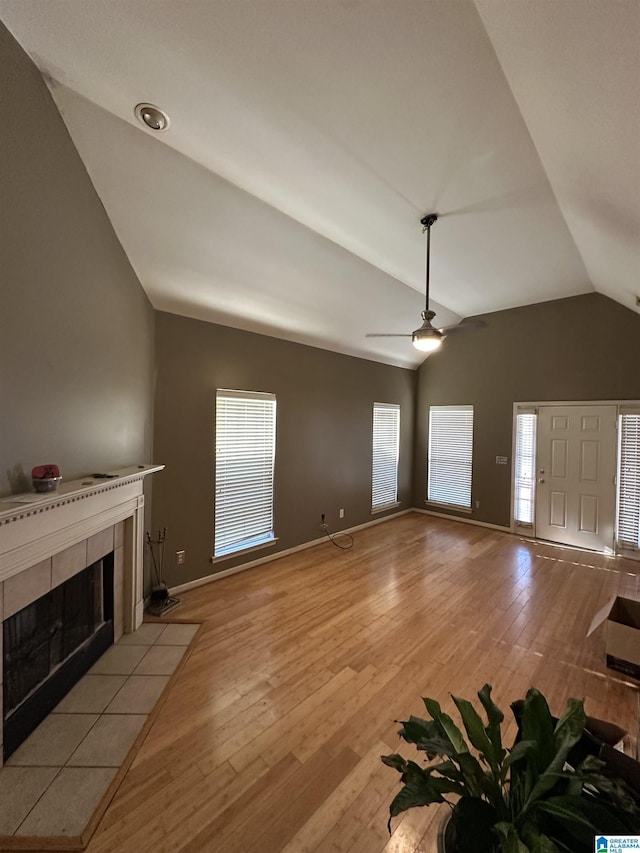 unfurnished living room with plenty of natural light, a fireplace, vaulted ceiling, and light wood-type flooring