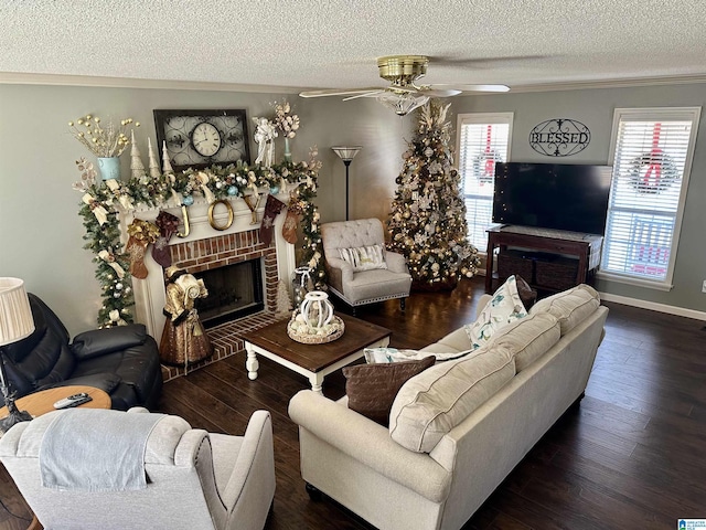 living room featuring a brick fireplace, a textured ceiling, ceiling fan, dark wood-type flooring, and crown molding