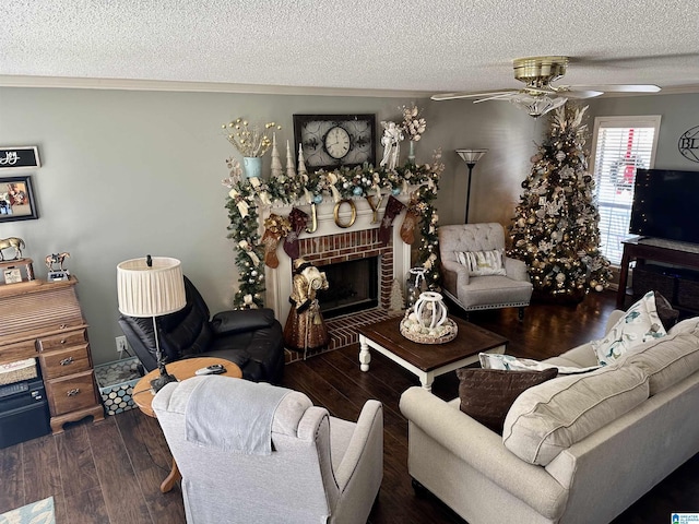 living room with a textured ceiling, a brick fireplace, ceiling fan, and dark wood-type flooring