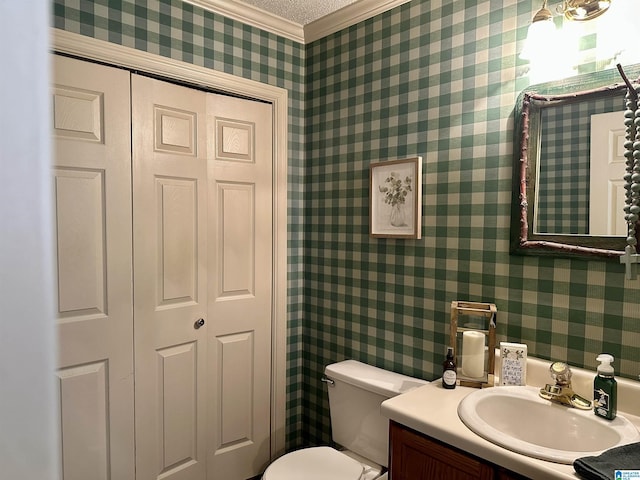 bathroom with toilet, vanity, a textured ceiling, and ornamental molding