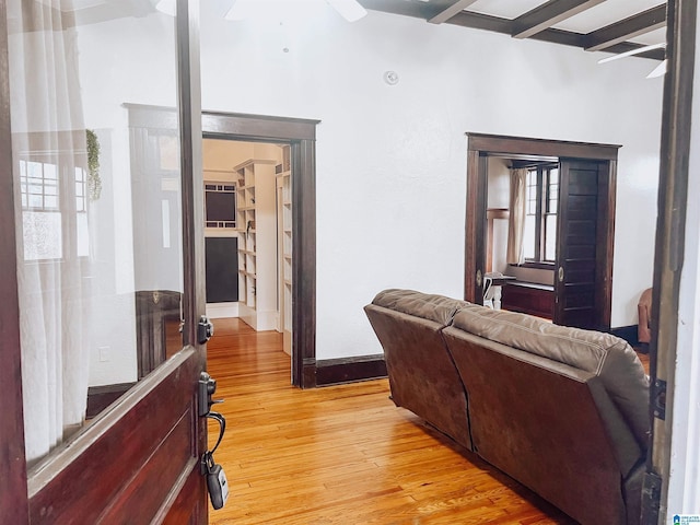 living room featuring beam ceiling, ceiling fan, and light hardwood / wood-style flooring